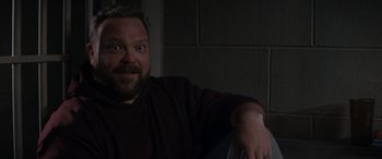 Movie still from “A Christmas Mystery” (2022), directed by Alex Ranarivelo – A person sitting in a chair near a brick wall; Close Up shot, High angle