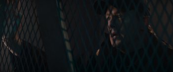 Movie still from “A Christmas Mystery” (2022), directed by Alex Ranarivelo – A man in a baseball cap looking through a fence at night; Close Up shot, Low angle