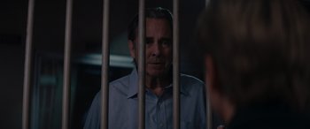 Movie still from “A Christmas Mystery” (2022), directed by Alex Ranarivelo – A man standing behind a metal fence looking at the camera; Close Up shot, Over the shoulder angle