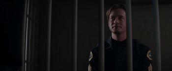 A police officer standing behind bars in a jail cell