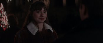 Movie still from “A Christmas Mystery” (2022), directed by Alex Ranarivelo – A woman in a brown jacket is smiling for the camera; Close Up shot, Over the shoulder angle