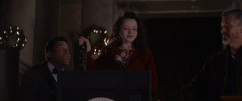 Movie still from “A Christmas Mystery” (2022), directed by Alex Ranarivelo – A young girl holding a microphone in front of a podium; Medium shot, Over the shoulder angle