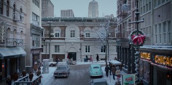 Movie still from “A Christmas Story Christmas” (2022), directed by Clay Kaytis – People walking on the sidewalk in the snow near a building; Extreme Wide shot, High angle