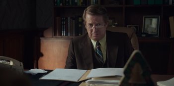 Movie still from “A Christmas Story Christmas” (2022), directed by Clay Kaytis – An older man sitting at a desk in front of papers; Medium shot, Over the shoulder angle