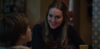 Movie still from “A Christmas Story Christmas” (2022), directed by Clay Kaytis – A young woman smiles while sitting at a table with a young boy; Close Up shot, Over the shoulder angle