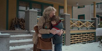 Movie still from “A Christmas Story Christmas” (2022), directed by Clay Kaytis – A woman and a boy hug in front of a house; Medium shot, Over the shoulder angle