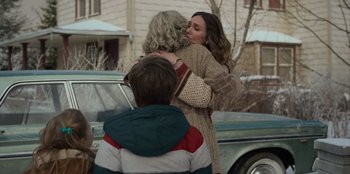 Two people hugging each other in front of a car
