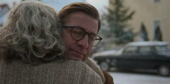 An older woman hugging a younger woman wearing glasses