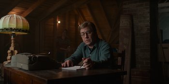 Movie still from “A Christmas Story Christmas” (2022), directed by Clay Kaytis – A man sitting at a table writing in a notebook; Medium shot, Low angle
