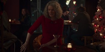 Movie still from “A Christmas Story Christmas” (2022), directed by Clay Kaytis – A woman sitting at a table with a drink in a glass; Medium shot, Over the shoulder angle