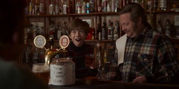 Movie still from “A Christmas Story Christmas” (2022), directed by Clay Kaytis – A man and a boy sitting at a bar with drinks; Medium shot, Over the shoulder angle