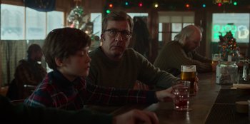 Movie still from “A Christmas Story Christmas” (2022), directed by Clay Kaytis – A man and a boy sitting at a table in front of a christmas tree; Medium shot, Over the shoulder angle