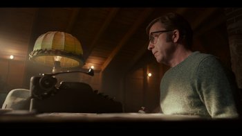 Movie still from “A Christmas Story Christmas” (2022), directed by Clay Kaytis – A man sitting in front of a desk with a lamp on top of it; Medium shot, Low angle