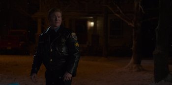 Movie still from “A Christmas Story Christmas” (2022), directed by Clay Kaytis – A man in a police uniform standing in the dark; Medium shot, Over the shoulder angle