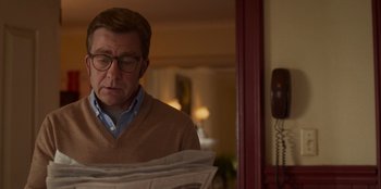 Movie still from “A Christmas Story Christmas” (2022), directed by Clay Kaytis – A man reading a newspaper while standing in front of a phone; Close Up shot, Over the shoulder angle