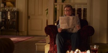Movie still from “A Christmas Story Christmas” (2022), directed by Clay Kaytis – A man sitting in a chair reading a newspaper; Medium shot, Over the shoulder angle