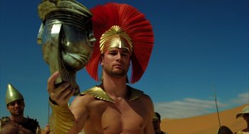 Movie still from “The Fall” (2006), directed by Tarsem Singh – A man in a gold and red helmet is holding a mask in his hand; Medium shot, Low angle