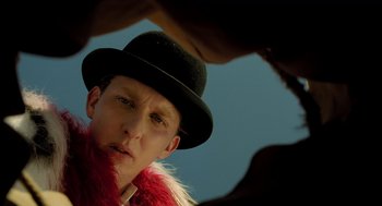 Movie still from “The Fall” (2006), directed by Tarsem Singh – A man in a black hat and a red feather boa; Close Up shot, Low angle