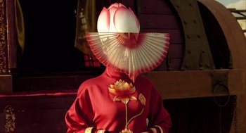 Movie still from “The Fall” (2006), directed by Tarsem Singh – A person wearing a red and white hat and holding a fan; Medium shot, Low angle