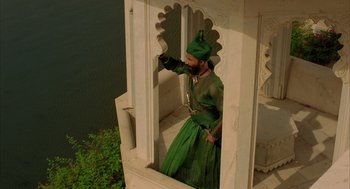 Movie still from “The Fall” (2006), directed by Tarsem Singh – A man dressed in a green outfit standing on a balcony; Wide shot, High angle