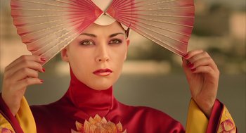 A woman in a red outfit holding a pink fan