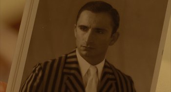 Movie still from “The Fall” (2006), directed by Tarsem Singh – A man wearing a suit and tie in sepia tone; Close Up shot, High angle