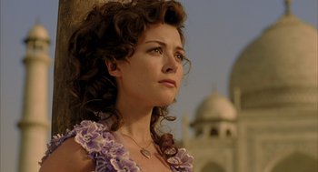 A woman with curly hair wearing a purple dress
