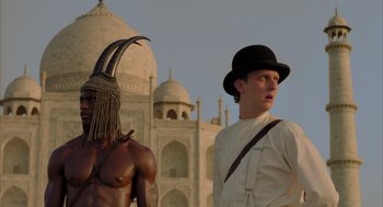 Movie still from “The Fall” (2006), directed by Tarsem Singh – A man in a top hat stands next to an african man; Medium shot, Low angle