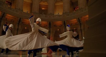 Movie still from “The Fall” (2006), directed by Tarsem Singh – A group of men performing a dance in front of a large building; Wide shot, Low angle