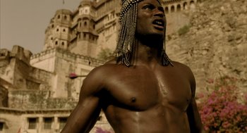 Movie still from “The Fall” (2006), directed by Tarsem Singh – A shirtless man with long hair is standing in front of a castle; Close Up shot, Low angle