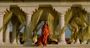 Movie still from “The Fall” (2006), directed by Tarsem Singh – A woman dressed in orange standing in front of pillars; Wide shot, Low angle