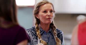 Movie still from “A Cowgirl's Song” (2022), directed by Timothy Armstrong – A woman with long blonde plaits wearing an apron; Close Up shot, Over the shoulder angle