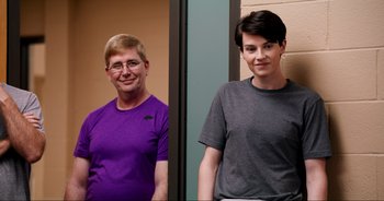 Movie still from “A Cowgirl's Song” (2022), directed by Timothy Armstrong – A man and a woman standing next to each other in front of a wall; Medium shot, Low angle