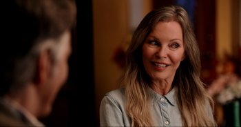 Movie still from “A Cowgirl's Song” (2022), directed by Timothy Armstrong – A woman smiles at the camera in front of a man; Close Up shot, Over the shoulder angle