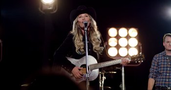 Movie still from “A Cowgirl's Song” (2022), directed by Timothy Armstrong – A woman in a cowboy hat holding a guitar; Medium shot, Low angle