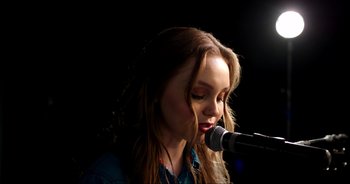 Movie still from “A Cowgirl's Song” (2022), directed by Timothy Armstrong – A woman with long hair is singing into a microphone; Close Up shot, Low angle
