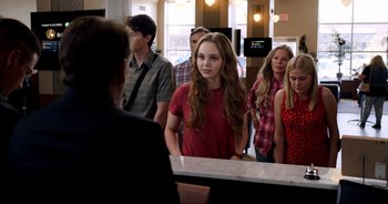 Movie still from “A Cowgirl's Song” (2022), directed by Timothy Armstrong – A group of people standing around a counter; Medium shot, Over the shoulder angle
