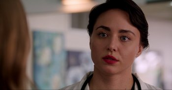 Movie still from “A Cowgirl's Song” (2022), directed by Timothy Armstrong – A person wearing a lab coat and stethoscope; Close Up shot, Over the shoulder angle