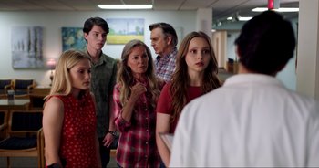Movie still from “A Cowgirl's Song” (2022), directed by Timothy Armstrong – A group of people standing in a room; Medium shot, Over the shoulder angle