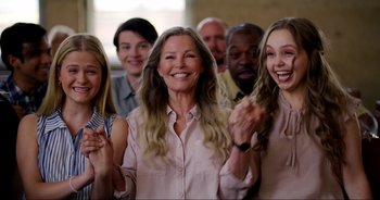 Movie still from “A Cowgirl's Song” (2022), directed by Timothy Armstrong – A group of people clapping and smiling for a picture; Medium shot, Over the shoulder angle