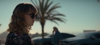 Movie still from “A Deadly Invitation” (2023), directed by J.M Cravioto – A woman wearing sunglasses standing in front of a palm tree; Close Up shot, Low angle