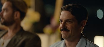 Movie still from “A Deadly Invitation” (2023), directed by J.M Cravioto – A person with a mustache smiling; Close Up shot, Over the shoulder angle