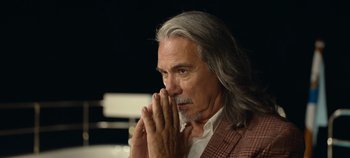 Movie still from “A Deadly Invitation” (2023), directed by J.M Cravioto – An older man with long gray hair is praying; Close Up shot, Low angle
