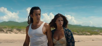 Movie still from “A Deadly Invitation” (2023), directed by J.M Cravioto – A man and a woman standing next to each other on the beach; Medium shot, Low angle