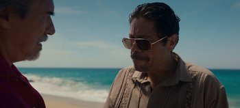 Movie still from “A Deadly Invitation” (2023), directed by J.M Cravioto – A person wearing sunglasses near the ocean; Close Up shot, Over the shoulder angle