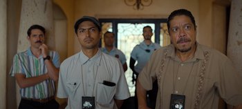 Movie still from “A Deadly Invitation” (2023), directed by J.M Cravioto – A group of men standing next to each other in front of a door; Medium shot, Low angle