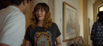 Movie still from “A Deadly Invitation” (2023), directed by J.M Cravioto – A woman standing in front of a painting; Medium shot, Over the shoulder angle