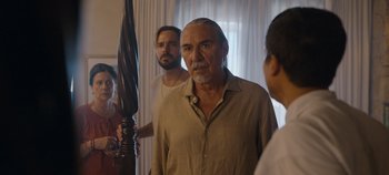 Movie still from “A Deadly Invitation” (2023), directed by J.M Cravioto – A group of people standing in front of a mirror; Medium shot, Over the shoulder angle