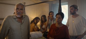 Movie still from “A Deadly Invitation” (2023), directed by J.M Cravioto – A group of people sitting in front of a bathroom mirror; Medium shot, Over the shoulder angle