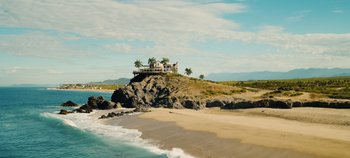 Movie still from “A Deadly Invitation” (2023), directed by J.M Cravioto – A house sitting on top of a hill near the ocean; Extreme Wide shot, High angle
